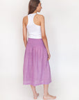 Woman wearing a white top and purple checkered skirt on a white background